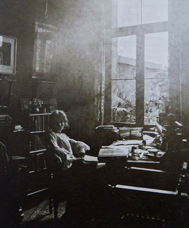Die schwarz-weiß-Fotografie zeigt Marie Luise Gothein in einem dunklen Zimmer mit großem fenster.
